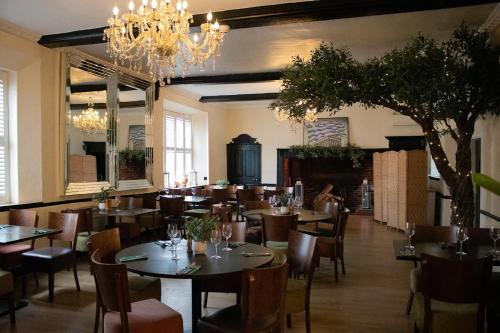 a restaurant with tables and chairs and a chandelier at The Scole Hotel in Scole