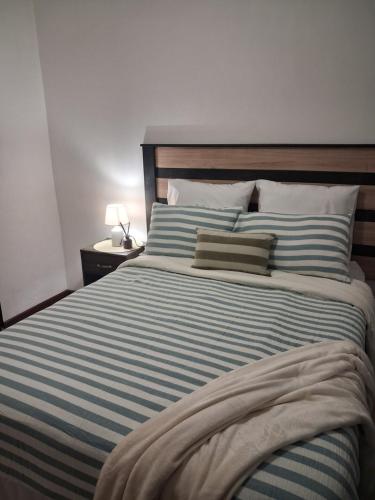 a large bed with a blue and white striped blanket at Trendy Tranquility in Secunda