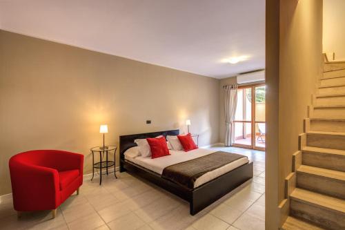 Inn Bracciano Suite Casa Vacanze في براتشيانو: غرفة نوم بسرير وكرسي احمر