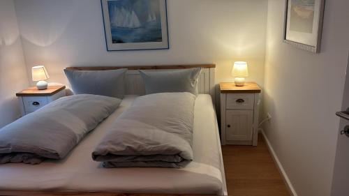 a bed with two pillows and two lamps on the sides at Heefkant Haus Heefkant, HK 03 in Rantum