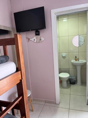 a bathroom with a toilet and a tv on the wall at Pousada da Igreja in Pântano Grande
