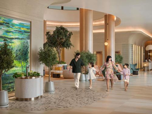 a man and woman and two children walking through a lobby at Pullman Resort Al Marjan Island in Ras al Khaimah