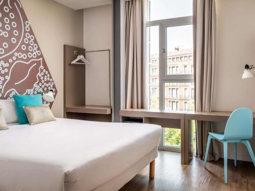a bedroom with a bed and a desk and a window at ibis Styles Barcelona Centre in Barcelona