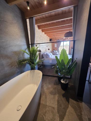 a bathroom with a bath tub and a bedroom at Rosa Carmel in Dāliyat el Karmil