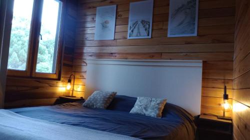 a bedroom with wooden walls and a bed with two lamps at Alma in Pinamar