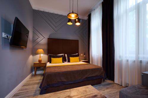 a bedroom with a bed with yellow pillows and a tv at REGINA Bed&Wine in Varna City