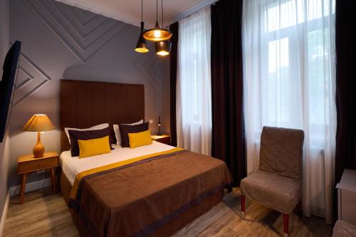a bedroom with a bed with yellow pillows and a chair at REGINA Bed&Wine in Varna City