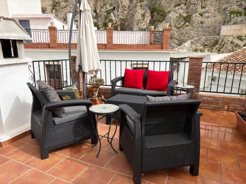 a patio with chairs and a couch and an umbrella at La Vieja Botica in Canillas de Aceituno