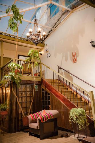 a room with a staircase with a couch and plants at Hostal Mallqui in Cusco
