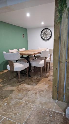 a dining room with a table and chairs and a clock at La coconing in Vierzon
