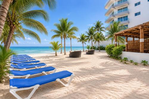 a row of blue lounge chairs on the beach at Arenika Beachfront Villa & Rooms in Puerto Morelos