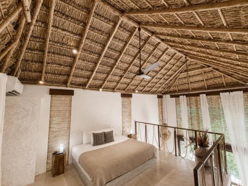 a bedroom with a bed and a wooden ceiling at Ikal Bungalows Tulum in Tulum
