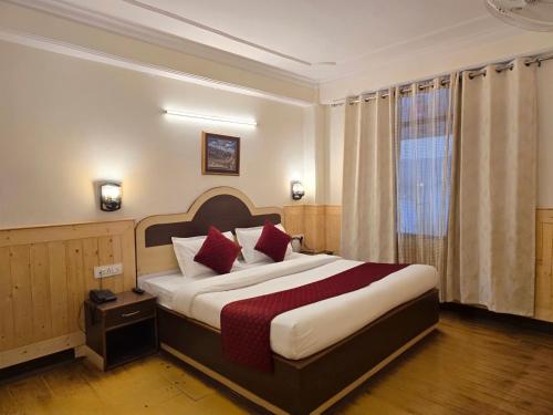 a hotel room with a large bed with red pillows at The Baris Haridwar in Haridwār