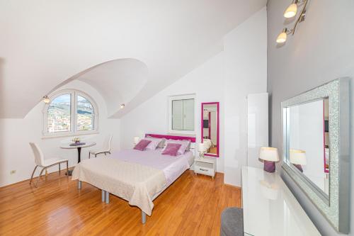 a white bedroom with a bed and a table at Apartmani Villa Biočić in Split