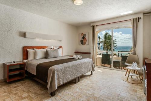 a bedroom with a bed with a view of the ocean at Luciana Hotel & Beach Club in Playa del Carmen