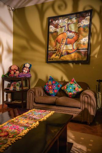 a living room with a couch and a painting on the wall at Hostal Mallqui in Cusco