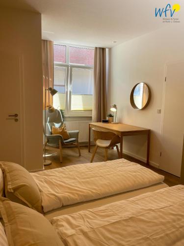 a bedroom with a bed and a desk and a chair at Stine's Hus Ferienwohnung 1 in Borkum