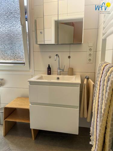 a white bathroom with a sink and a mirror at Stine's Hus Ferienwohnung 1 in Borkum