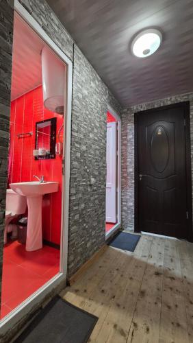 a bathroom with a sink and a red wall at Chvibiani Guesthouse & Bar in Ushguli
