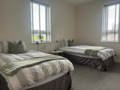 two beds in a room with two windows at Kilnhill in Hawick