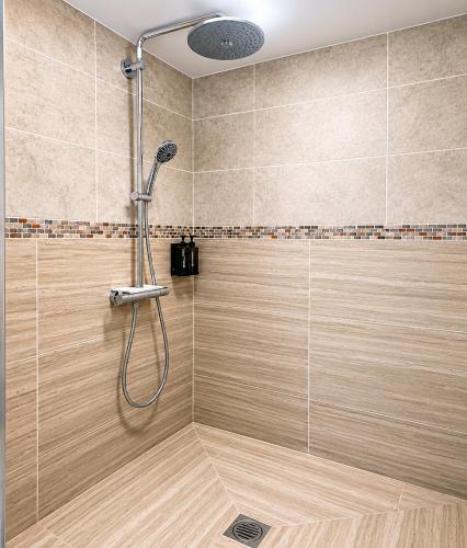 a shower with a shower head in a bathroom at Aron Guest House in Ealing
