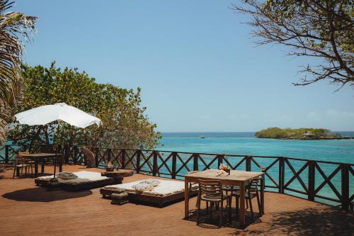a patio with tables and chairs and a view of the water at Isla Única- Islas del Rosario in Isla Grande