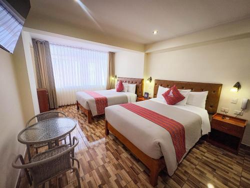 a hotel room with two beds and a table at Hotel Sky Mirador in Cusco