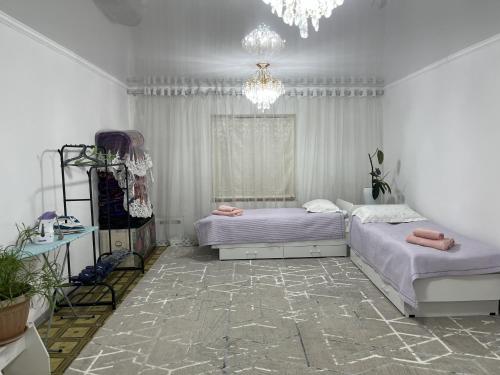 a bedroom with two beds and a chandelier at Friendly House in Bokonbayevo
