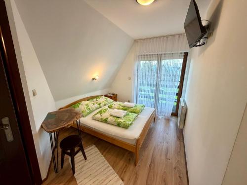 a bedroom with a bed with green pillows and a television at U Szaflarskich in Bańska Niżna