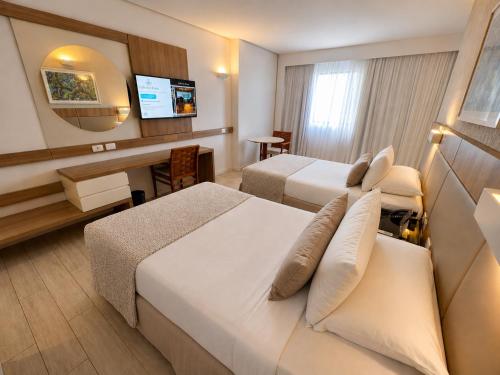 a hotel room with two beds and a flat screen tv at Mar Hotel Conventions in Recife