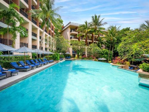 a swimming pool at a resort with blue chairs and palm trees at Novotel Phuket Kata Avista Resort and Spa in Kata Beach