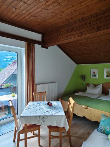 a bedroom with a bed and a table and chairs at Blumenpension Strauss - Ferienwohnungen in Ossiach