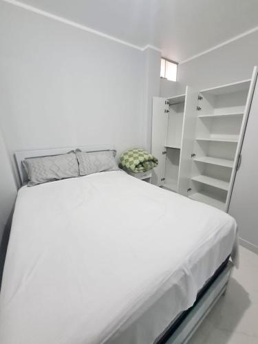 a bedroom with a white bed and a white shelf at Montecarlo Hospedaje in Tacna