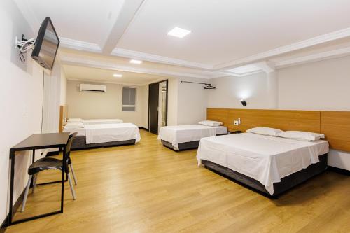 a room with three beds and a desk in it at Hotel Move BH in Belo Horizonte