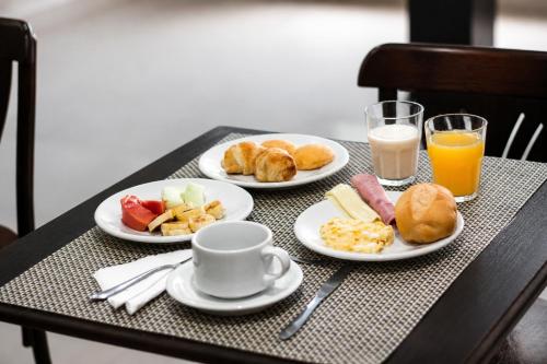 a table with three plates of breakfast food and orange juice at Letto Business in Porto Alegre