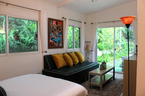 a bedroom with a bed and a couch and windows at Nan La Tigra in El Rosario
