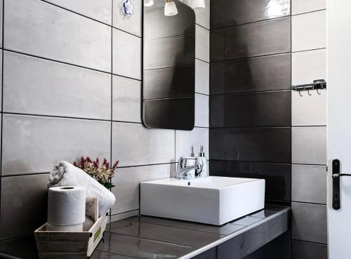 a bathroom with a white sink and black tiles at Aegli House in Theológos