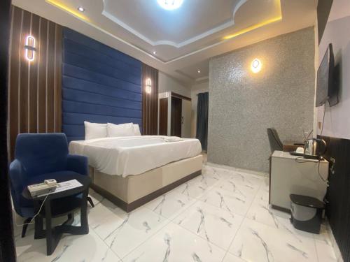 a hotel room with a bed and a chair at Spenza Hotel and Suites in Asaba