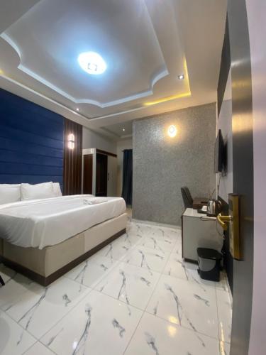 a hotel room with a bed and a desk and a television at Spenza Hotel and Suites in Asaba