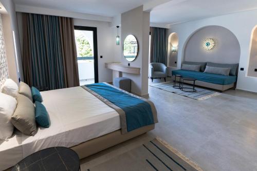 a bedroom with a large bed and a living room at Hôtel Hammamet Beach in Hammamet