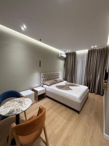 a bedroom with a bed and a table and a chair at Gysi`s Hotel & Restaurant - Near Tirana in Tapizë