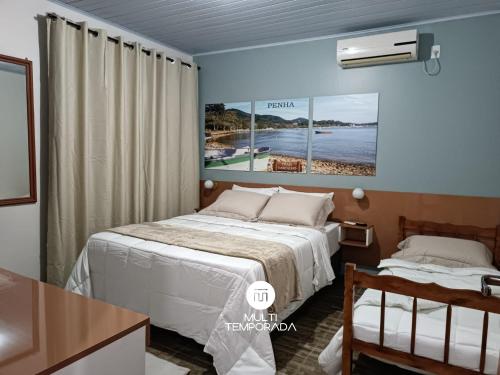 a hotel room with a bed and a desk and a window at Pousada Família Cordeiro - Penha/SC in Penha