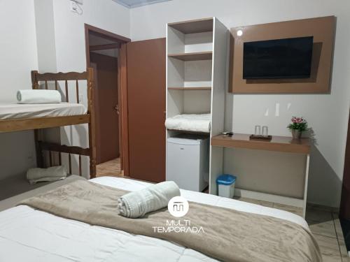 a bedroom with two bunk beds and a tv at Pousada Família Cordeiro - Penha/SC in Penha