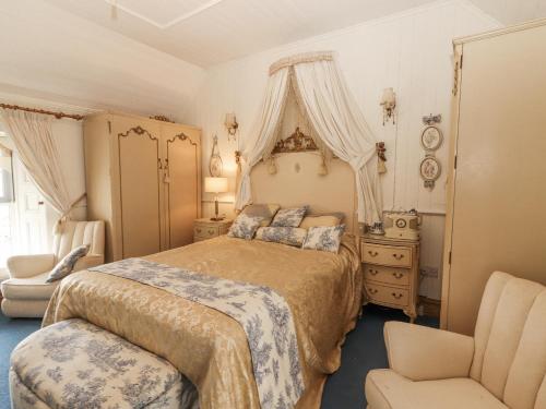 a bedroom with a large bed and a chair at White Heather Cottage in Killaloe