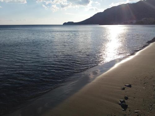 a beach with the sun shining on the water at San Georgio Hotel in Tsoútsouros