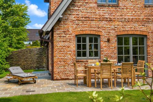 a patio with a table and chairs in front of a brick building at Haus Friesenkrone in Braderup