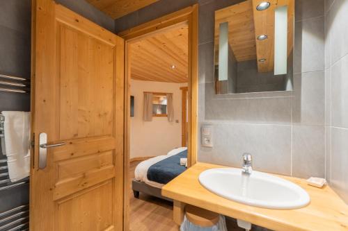 a bathroom with a sink and a bed at Le Cosy - Appartement in Les Gets