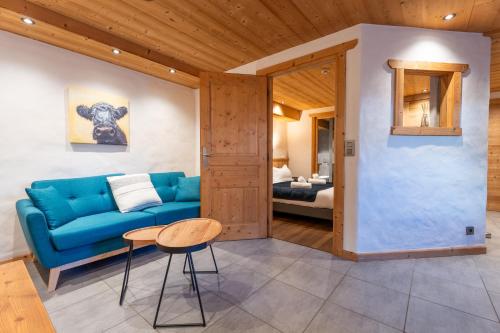 a living room with a blue couch and a bedroom at Le Cosy - Appartement in Les Gets