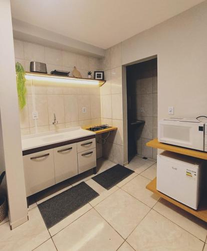 a kitchen with a sink and a microwave at Apartamento 11 - 2 Quartos com AC e cama de casal in Toledo