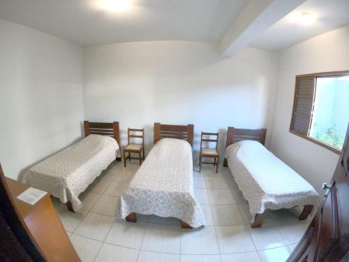 a room with three beds with chairs and a window at Casa Alceste - Casa inteira, com garagem privativa, a 10 minutos a pé do Centro Histórico de Diamantina - 05 hóspedes in Diamantina